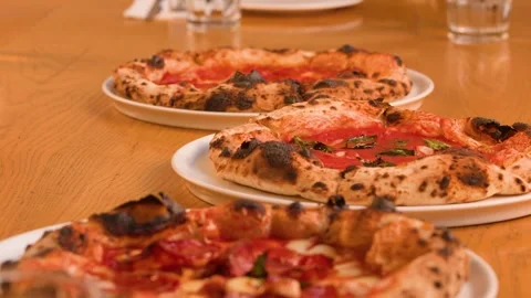 Server Placing Fresh Neapolitan Pizzas on a Wooden Restaurant Table Stock Footage 338053922