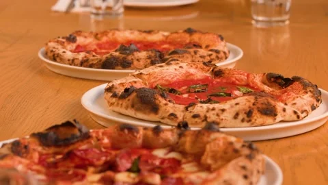 Server Placing Fresh Neapolitan Pizzas on a Wooden Restaurant Table Stock Footage 338421018