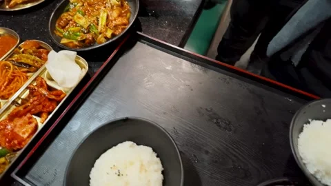 Server Placing Korean Stir Fry and Rice Bowls on Restaurant Table Stock Footage 340183103