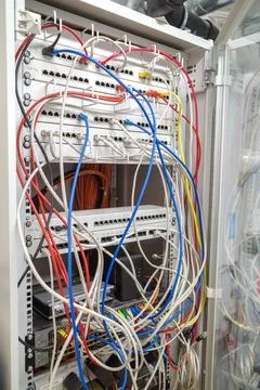 In a server rack many different colored network cables are connected to the.. Stock Photos