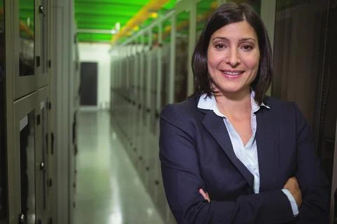 Server racks are lining modern data center aisle, featuring green and orange Stock Photos