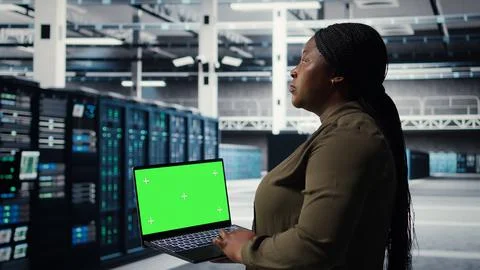 Server room admin uses green screen laptop to upgrade mainframes Stock Photos