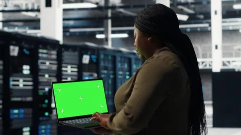 Server room admin uses green screen laptop to upgrade mainframes Stock Photos
