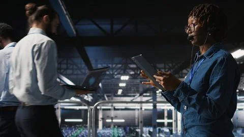 Server room admin uses tablet and headset to provide infrastructure tech support Foto stock