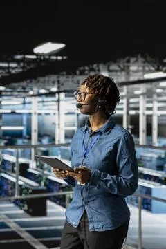Server room admin using tablet and headset microphone to provide tech support Stock Photos
