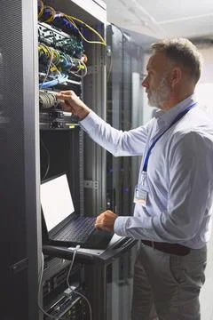 Server room, engineer and connection with laptop for cybersecurity, maintenance Stock Photos
