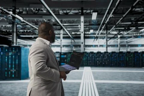 Server room IT expert using programming scripts on laptop, doing debugging 库存照片