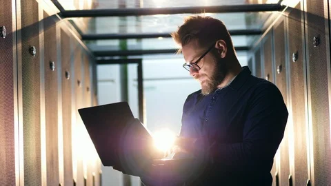 Server room with a man operating a laptop in a flashlight. Datacenter server Stock Footage 111291162