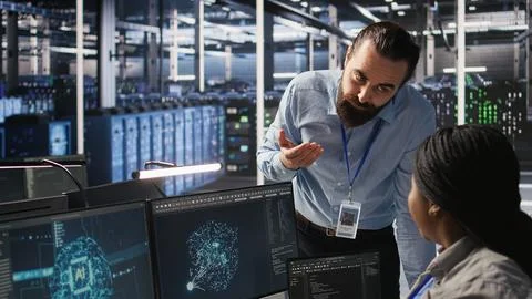 Server room manager providing feedback to employee managing AI datasets Foto stock