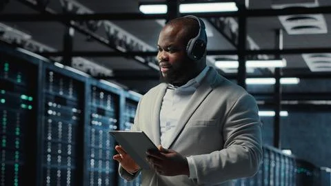 Server room programmer wearing headphones troubleshooting errors Foto stock