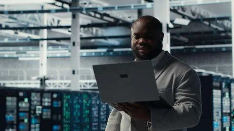 Server room worker auditing systems for vulnerabilities using software on laptop Foto stock