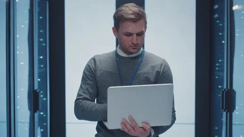 Server specialist works on laptop in server corridor analyzing neural network Stock Footage 125519236