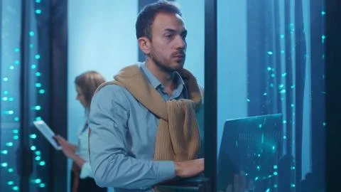 Server tech support with headset performing data operations in server room. His Foto stock