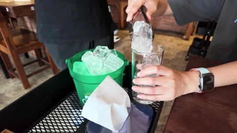 Server Using Tongs to Place Ice into Glass at Restaurant Stock Footage 343505635