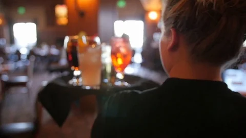Server walks with tray of drinks through restaurant with daylight shining Stockbeeldmateriaal 86443329