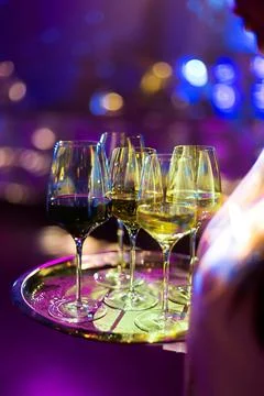 A server's tray holding multiple wine glasses with different coloured beverag Stock Photos