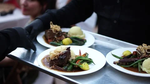 Servers tray passing ribeye steaks at a beautiful outdoor wedding. Stock Footage 223101108