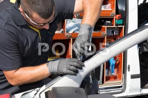 Service agent man repairs windhield at work Stock Photos