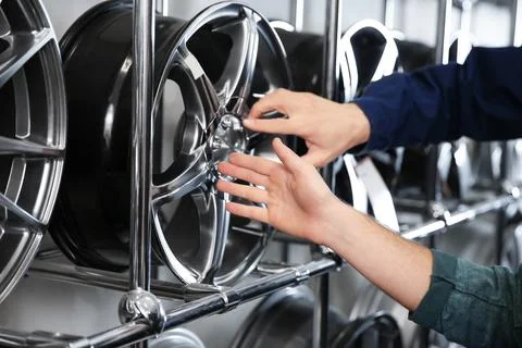 Service center consultant and customer near alloy wheels in store, closeup Stock Photos