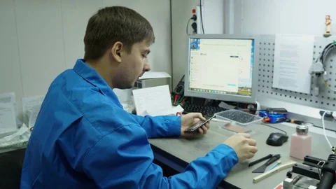 Service center. Electronics repair shops. The repair of the smartphone. Man Stock Footage 82758436