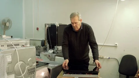 Service center. Electronics repair shops. A man repairs the hob. Multimeter. Stock Footage 82804751