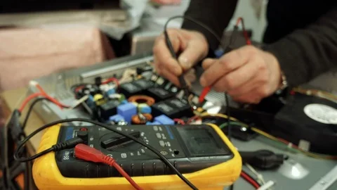 Service center. Electronics repair shops. A man repairs the hob. Multimeter. Stock Footage 82805756