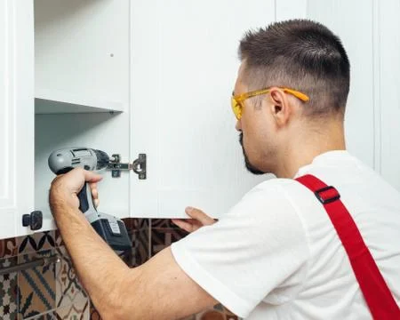 Service contractor using electric screwdriver while installing new furniture in Stock Photos