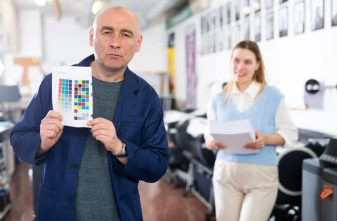 Service engineer demonstrating test page with color palette in his hand Stock Photos