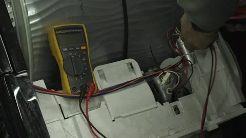 Service engineer testing and repairing a tumble dryer. Close up of male Stock Footage 146806624