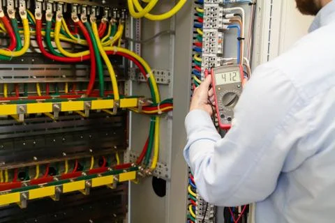Service engineer working with electric device for testing electrical cabinet. Stock Photos