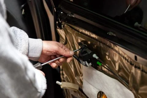 The service man opens a screwdriver with the inner handle of the car's interi Stock Photos