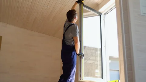 Service man in uniform installing pvc window with measure tape in wooden Stock Footage 244548631