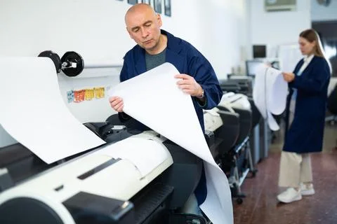 Service man uses plotter and checks functionality in printing shop Fotos de archivo