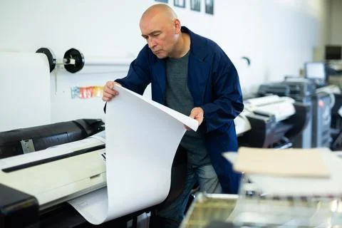 Service man uses plotter and checks functionality in printing shop Fotos de archivo