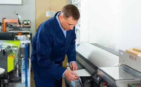 Service man uses plotter in printing shop Fotos de archivo