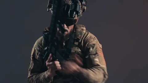 Service member in combat gear aims weapon forward, showcasing tactical readiness Stock Footage 336490628