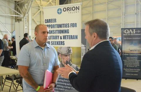 A service member listens to a hiring manager describe job openings during ... Stock Photos