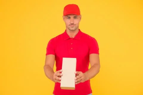 Service plus quality. Serious guy hold parcel yellow background. Man delivery 스톡 사진