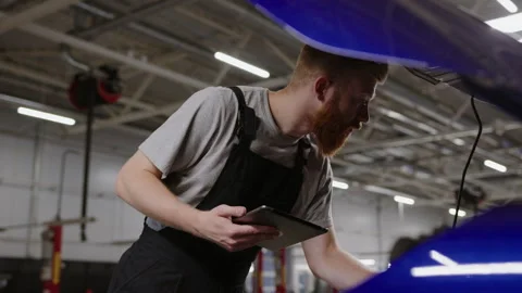 Service station.Mechanic with a tablet notes what to change during the repair Видео 253391876