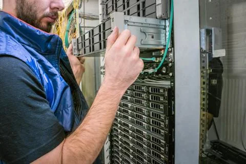 Service work on the technical platform. The man replaces the server in the ra 库存照片