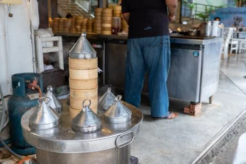 Service workers steaming dim sum steamed in bamboo baskets in a stainless ste Stock Photos
