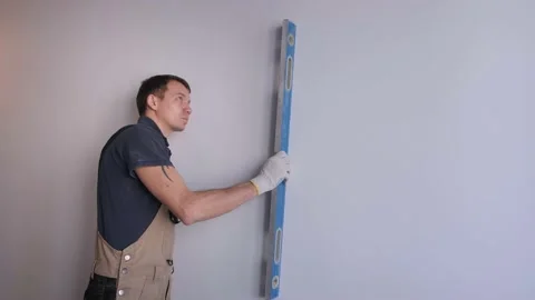 Serviceman measures wall evenness with blue waterpass Stock Footage 152850075
