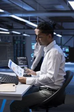 Serviceman in server hub checking documentation of supercomputers Stock Photos