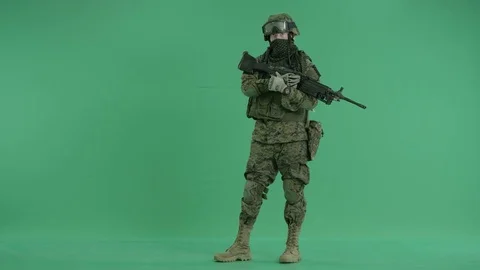 Serviceman standing with weapon and looking at camera at green screen 動画素材 70430993