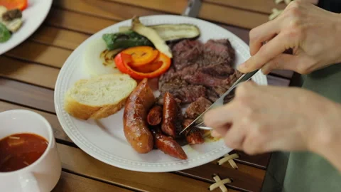 Serving and eating grilled BBQ meat on a plate outdoors. Full HD Stock Footage 328629336