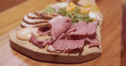 A serving of appetizers on a wooden serving board as the camera orbits around Stock Footage 236596406