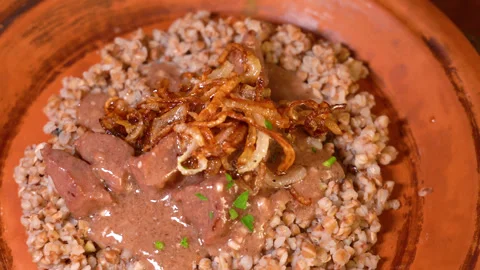 Serving of appetizing dish on table. Buckwheat, goulash with dill in plate. Stock Footage 248180952
