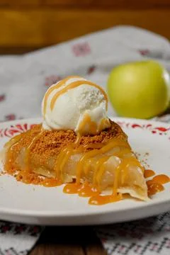 A serving of apple pie with vanilla ice cream on a plate. Stock Photos