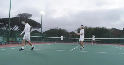 Serving Asian man bouncing ball initiating rally on outdoor court under Stock Footage 340979784