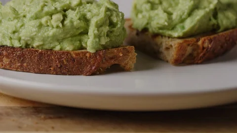 Serving avocado toast, putting smashed avocado on toasted bread 動画素材 128483277